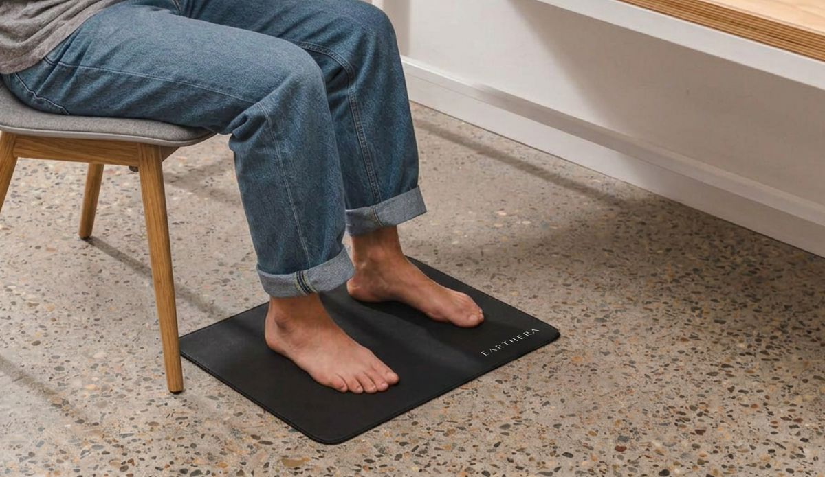 Bare feet on an EARTHERA grounding mat under a desk